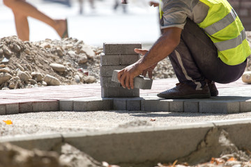 Worker puts sidewalk tile on the road