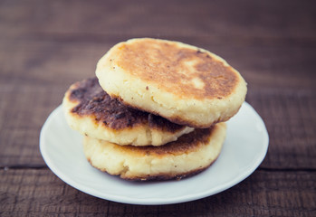 Cheese pancakes on white plate over dark rustic wooden backgroun