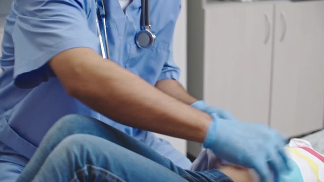 Tilt down of Latin-American doctor pressing on stomach of little patient and asking if it hurts