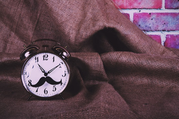 Alarm clock with a black hipster mustache Vintage Retro Filter.
