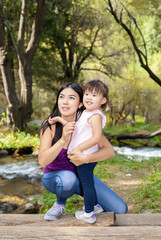 Fototapeta premium Asian Woman with her little daughter in the woods near the river standing on a log