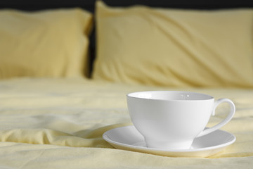 Fototapeta na wymiar hot cooffee in white cup on bed