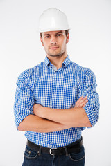Serious man architect in building helmet standing with arms crossed