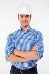 Happy man builder in hard hat standing with arms crossed