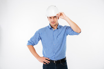 Serious young man building engineer in hard hat posing