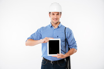 Cheerful man builder in hard hat showing blank screen tablet