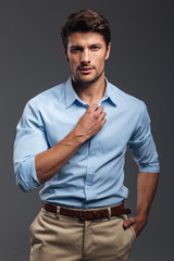 Portrait of a casual handsome man buttoning his shirt