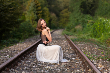 Naklejka premium Elegant woman sitting on railroad tracks