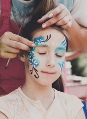 Female child face painting, making butterfly process