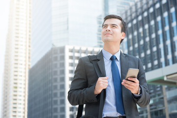 Fototapeta premium Young businessman using mobile phone while carrying bag in the city-business travel and mobile roaming concepts 
