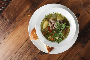 Chorba - traditional middle eastern soup in a white plate. Wooden background.