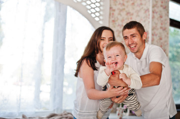 Cute caucasian baby boy laughs on arms of parents