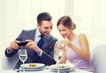 smiling couple with appetizers and smartphones