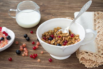 Homemade delicious healthy granola with nuts, seeds, honey and fresh berries in a ceramic cup on a wooden table