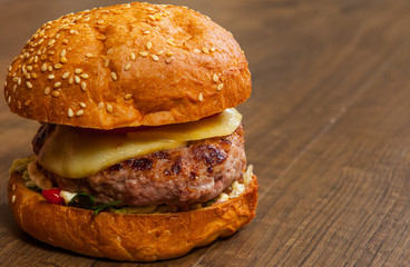 burger with meat, tomato, onion, cheese, lettuce, vegetables on wooden table. with copy space.