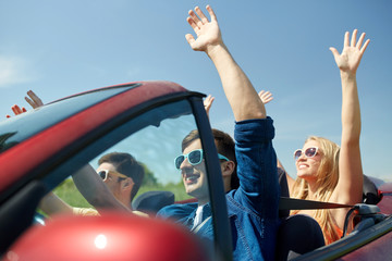 happy friends driving in cabriolet car at country