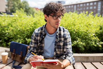 man with notebook or diary writing on city street