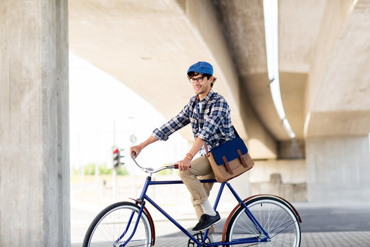 happy hipster man with bag riding fixed gear bike