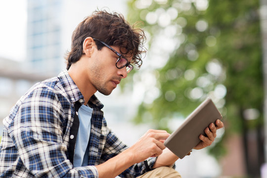 Fototapeta man with tablet pc sitting on city street bench