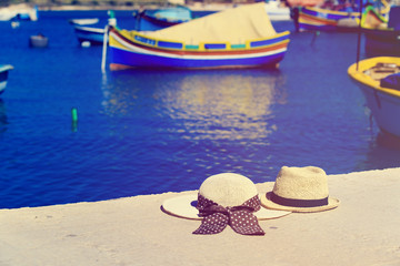 two hats with traditional maltese boats on background, travel in Malta
