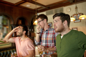 friends with beer watching sport at bar or pub