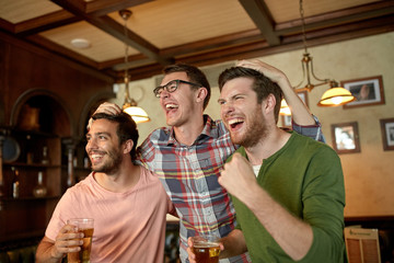 friends with beer watching sport at bar or pub