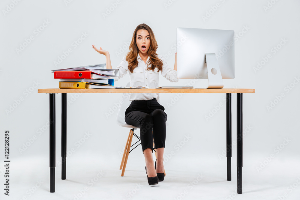 Wall mural surprised young businesswoman sitting at the table with pc