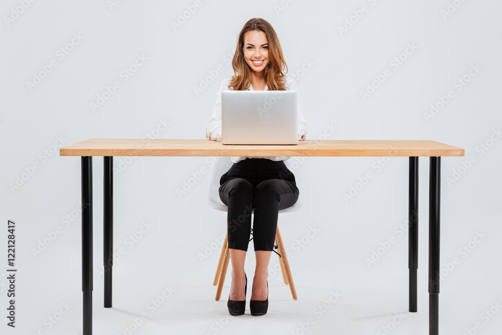 Canvas Prints Attractive smiling businesswoman using laptop while sitting at office desk