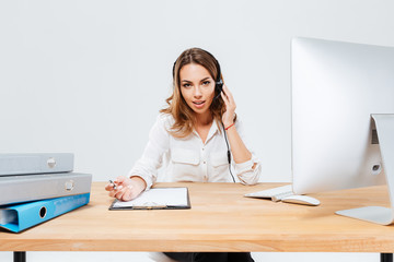 Young concentrated woman in headphones and microphone talking with client