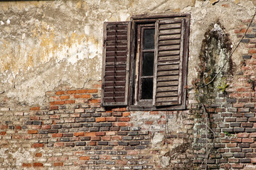 Old window on the broken wall and wooden shutter