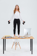 Full length of mad businesswoman standing on table and shouting
