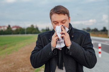  Young men is suffering from a cold while holding a handkerchief