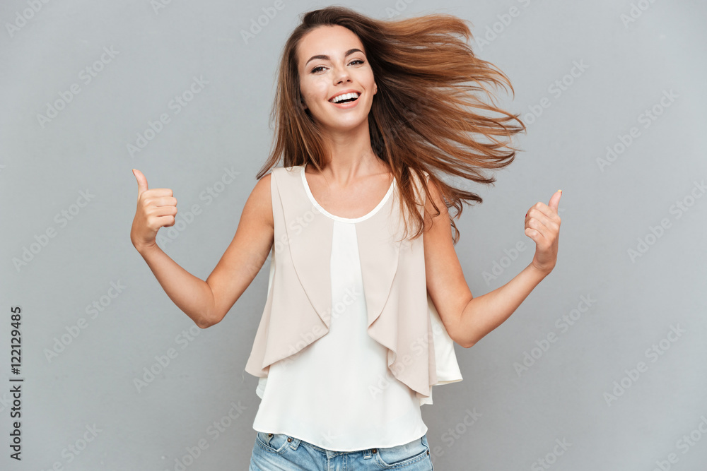 Wall mural portrait of a casual smiling young woman showing thumbs up