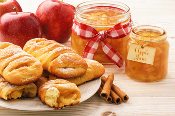 Fresh yeast buns with apple jam and cinnamon on white wooden background.