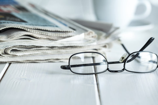 Stack of newspapers and eyeglasses
