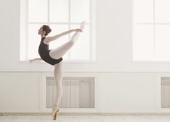 Beautiful ballerine stands in arabesque ballet position