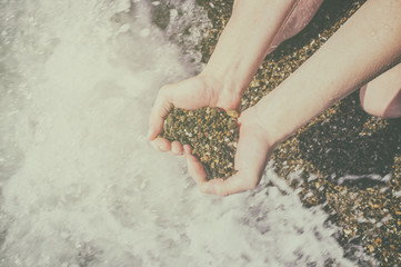 heart symbol from stones in a female hand on a background of the Black Sea. Conceptual design.
