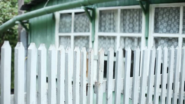 Views of a town. Old city streets. Panorama of an exterior of a green single-storey wooden house behind a white fence. HD