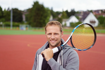 mann mit tennisschläger steht draußen auf einem sportplatz