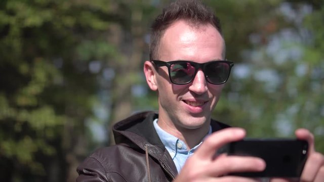 Young attractive happy man in sunglasses use videochat
