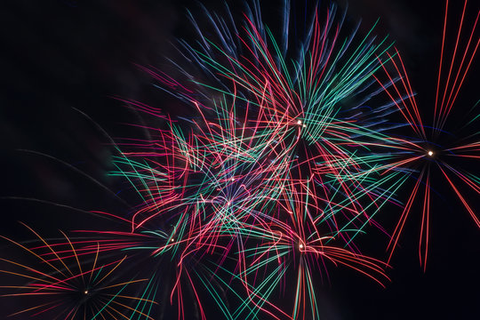 Red, pink, green and blue sparks of fireworks in the sky