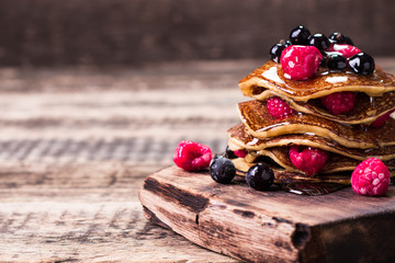 Buckwheat pancakes with berry fruit and honey on wooden vintage table