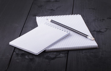 Pencil and notepad with spiral on black wooden