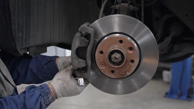 Car mechanic Repairing brakes on car in modern service workshop