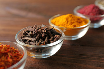 Assortment of spices in glass bowls on wooden background
