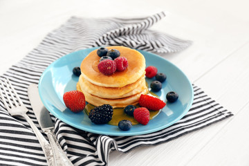 Plate with delicious pancakes and berries on striped napkin