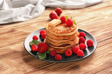 Tasty pancakes with berries and butter on plate