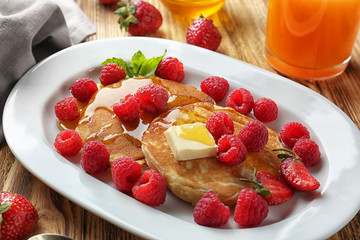 Tasty pancakes with berries, butter and honey on plate