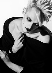 Freaky gothic fashion model boy with blonde hair, piercing and black make up in black mantle
