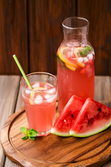 Watermelon lemonade with lemon and mint in a glass and a jug on